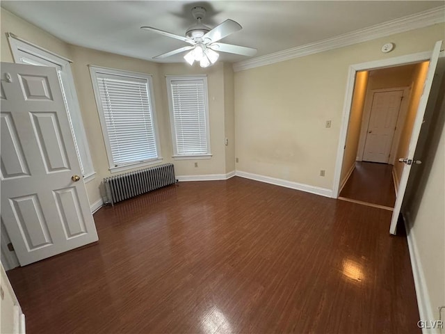 unfurnished bedroom featuring crown molding, baseboards, dark wood finished floors, radiator heating unit, and a ceiling fan