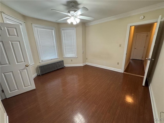 spare room featuring ornamental molding, dark wood finished floors, radiator, baseboards, and ceiling fan