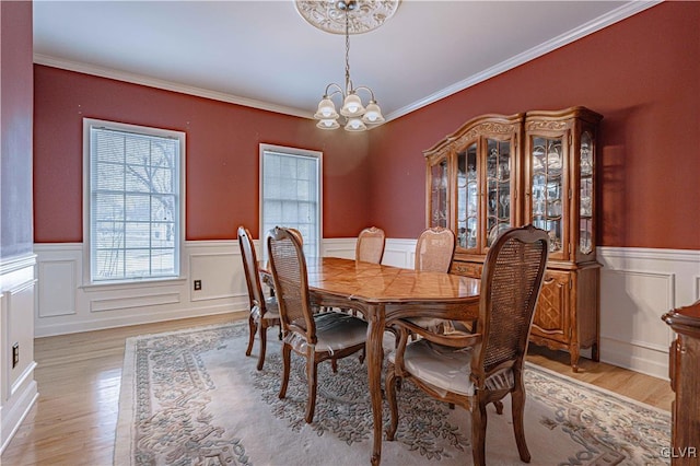 dining area featuring a chandelier, a wainscoted wall, light wood-style flooring, and crown molding