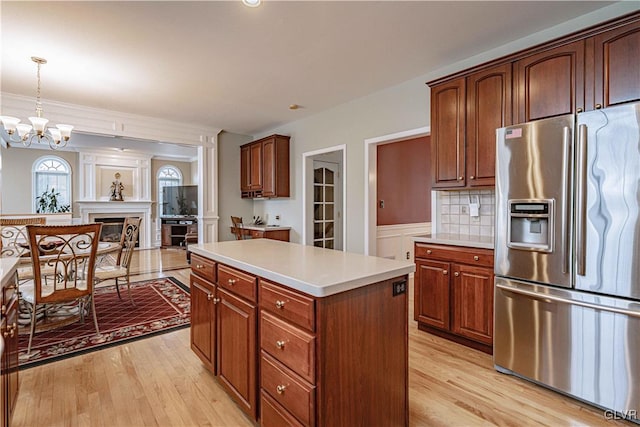 kitchen featuring light wood finished floors, stainless steel fridge, a center island, hanging light fixtures, and light countertops