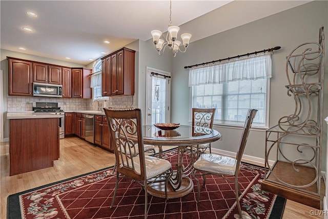 dining space featuring light wood-type flooring, recessed lighting, baseboards, and an inviting chandelier