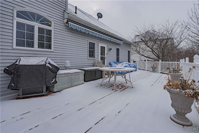 snow covered patio with area for grilling and a wooden deck