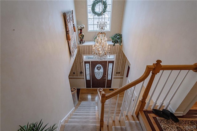 foyer entrance with an inviting chandelier, stairs, a high ceiling, and wood finished floors