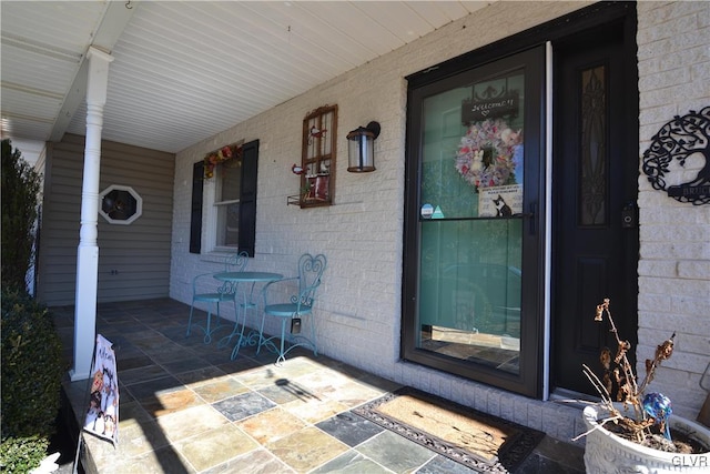 entrance to property featuring covered porch and brick siding