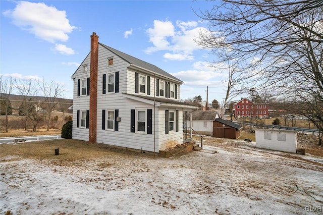 exterior space with a chimney, a storage unit, and an outdoor structure