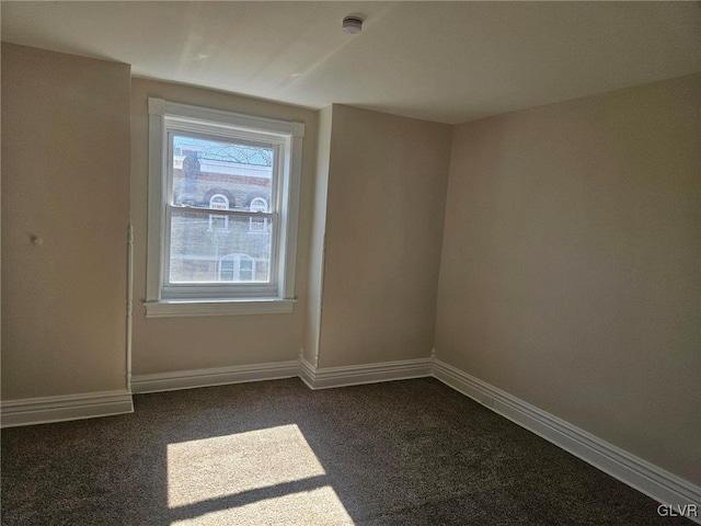 empty room with dark carpet and baseboards