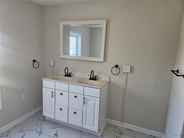 bathroom featuring marble finish floor, a sink, baseboards, and double vanity