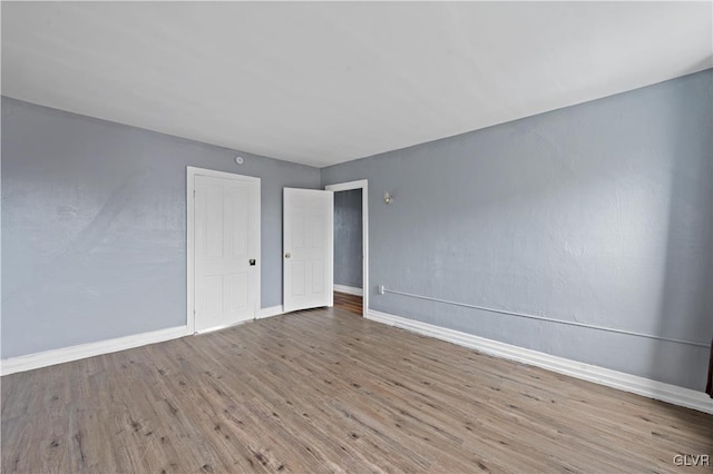 empty room featuring light wood-type flooring and baseboards