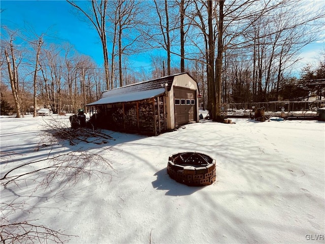 view of snow covered exterior with a garage, an outdoor fire pit, and an outbuilding