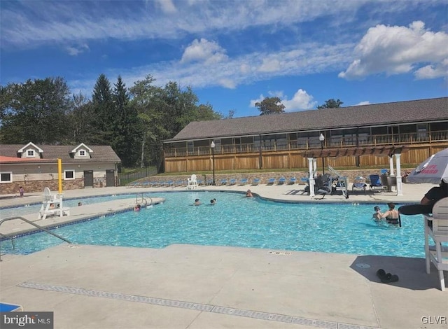 community pool with a patio and fence