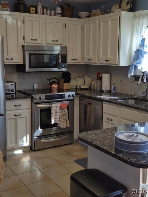 kitchen with light tile patterned floors, appliances with stainless steel finishes, and white cabinetry