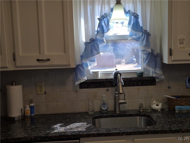 kitchen featuring dark stone counters, white cabinets, a sink, and decorative backsplash