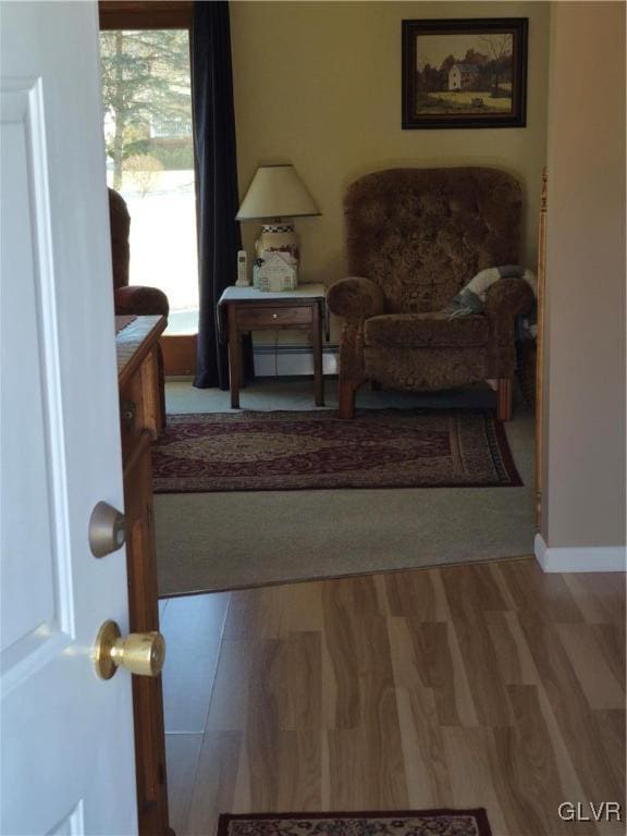 sitting room with baseboards, baseboard heating, and wood finished floors