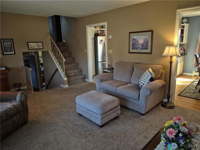 carpeted living area featuring baseboards and stairs