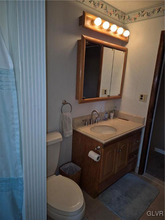 full bathroom featuring curtained shower, vanity, toilet, and wallpapered walls