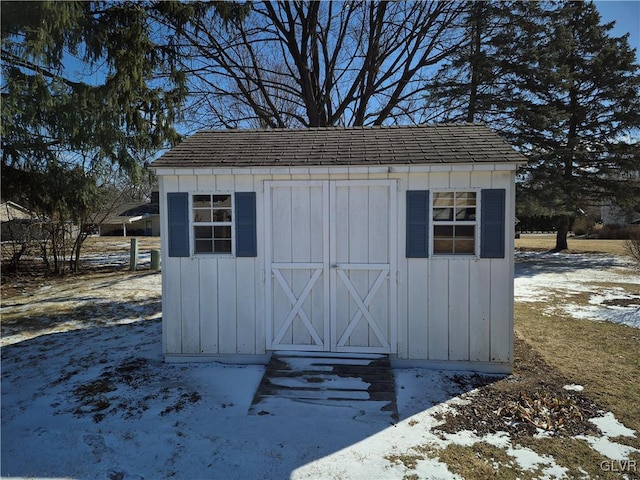 snow covered structure featuring an outbuilding and a storage shed