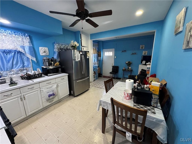 kitchen with a ceiling fan, stainless steel appliances, light countertops, light floors, and white cabinetry