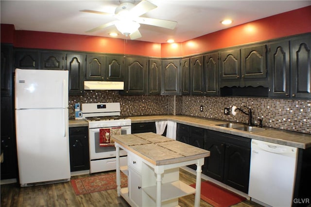 kitchen with white appliances, decorative backsplash, dark wood-style flooring, under cabinet range hood, and a sink