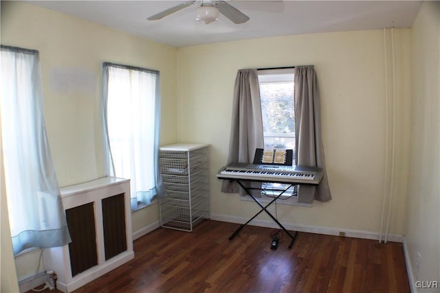 misc room featuring dark wood-style floors, a ceiling fan, and baseboards