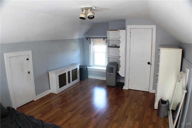 additional living space featuring dark wood-style floors, lofted ceiling, and baseboards