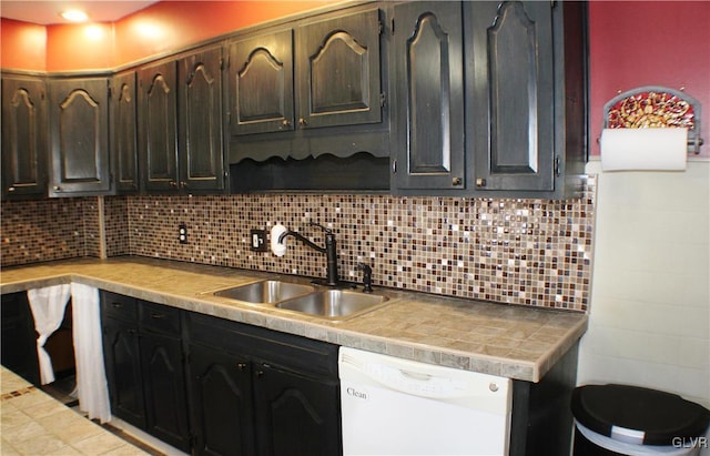 kitchen with light countertops, backsplash, white dishwasher, and a sink