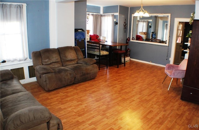 living area featuring baseboards, wood finished floors, and a notable chandelier