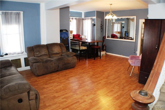 living room with a wealth of natural light, a notable chandelier, baseboards, and wood finished floors