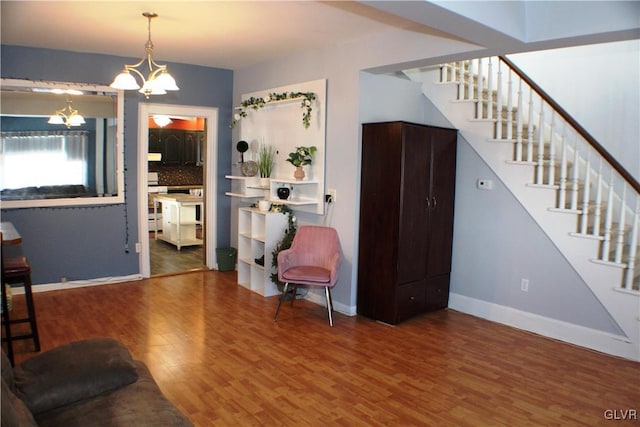 foyer entrance with a notable chandelier, stairway, baseboards, and wood finished floors