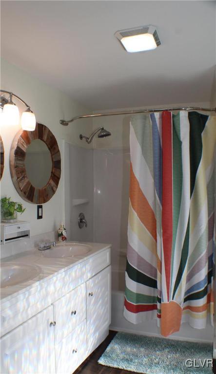 full bath featuring shower / bath combination with curtain, a sink, and double vanity