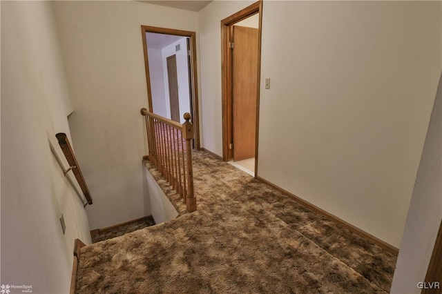 hallway featuring baseboards, light colored carpet, and an upstairs landing