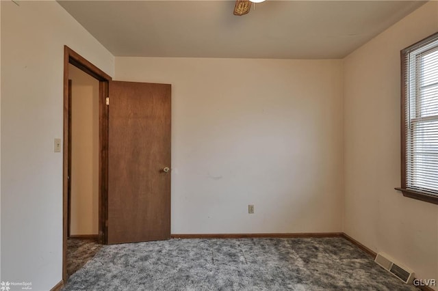 empty room with baseboards, visible vents, and dark carpet