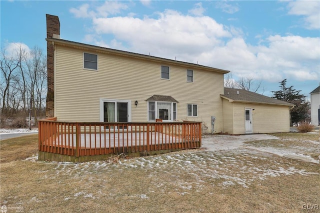 snow covered back of property featuring a chimney and a deck