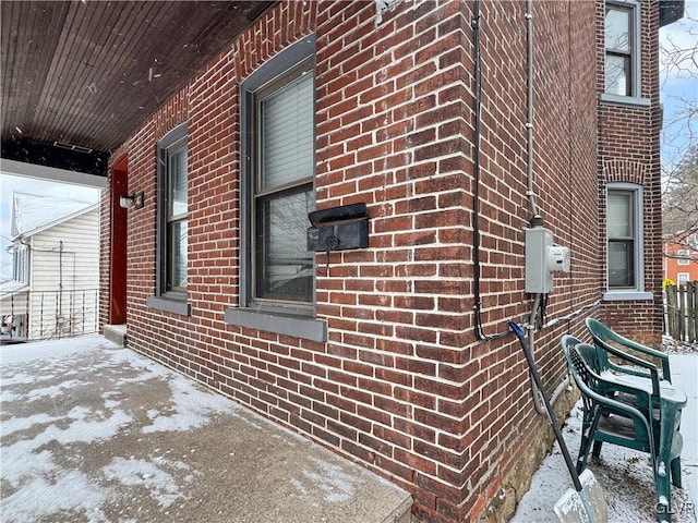 view of snow covered exterior featuring driveway and brick siding