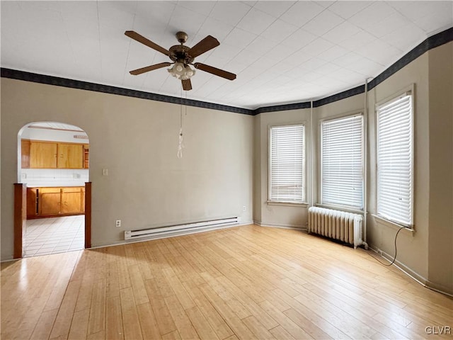 spare room with arched walkways, light wood-style floors, ornamental molding, baseboard heating, and radiator heating unit