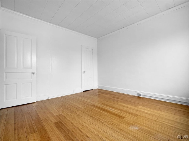 unfurnished room with baseboards, wood finished floors, and crown molding