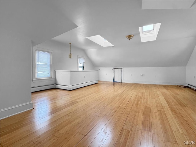 bonus room featuring vaulted ceiling with skylight, light wood finished floors, baseboard heating, and baseboards