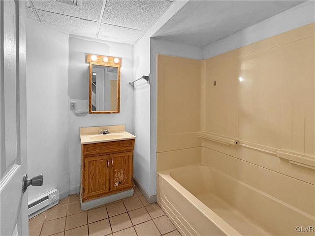 full bathroom with a drop ceiling, a baseboard radiator, vanity, baseboards, and tile patterned floors