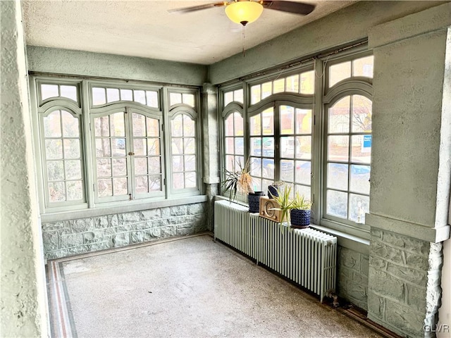 unfurnished sunroom featuring ceiling fan and radiator heating unit