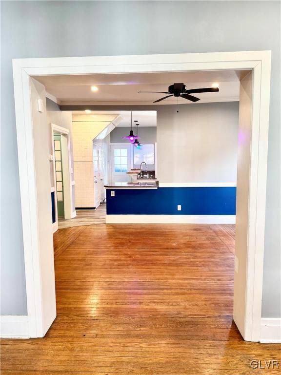 interior space with ceiling fan, light wood finished floors, a sink, and baseboards