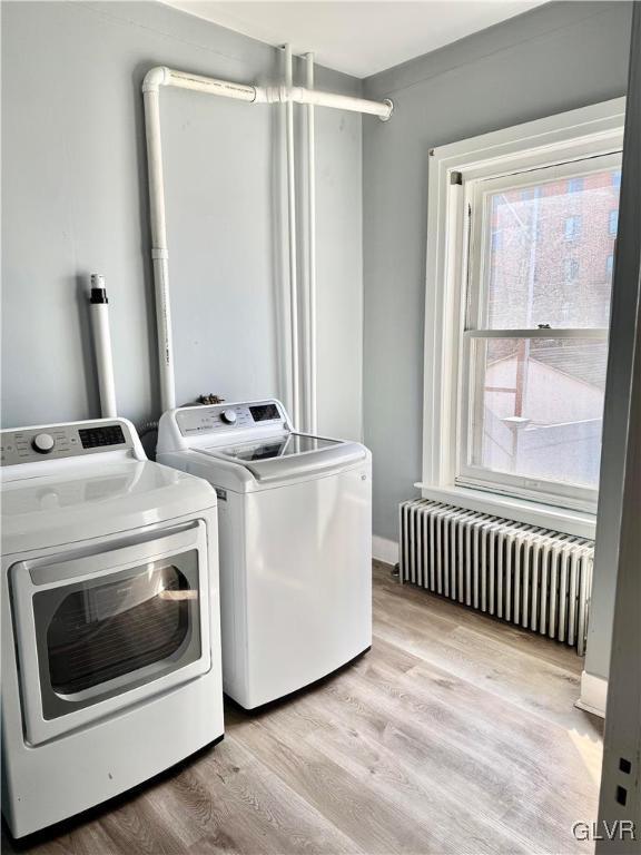 laundry area with light wood finished floors, radiator, laundry area, independent washer and dryer, and baseboards