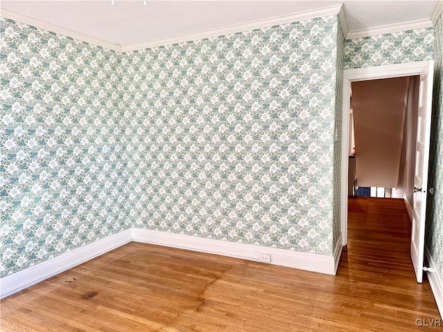 empty room featuring ornamental molding, wood finished floors, baseboards, and wallpapered walls