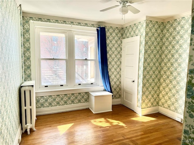 interior space with light wood-type flooring, crown molding, radiator heating unit, and wallpapered walls