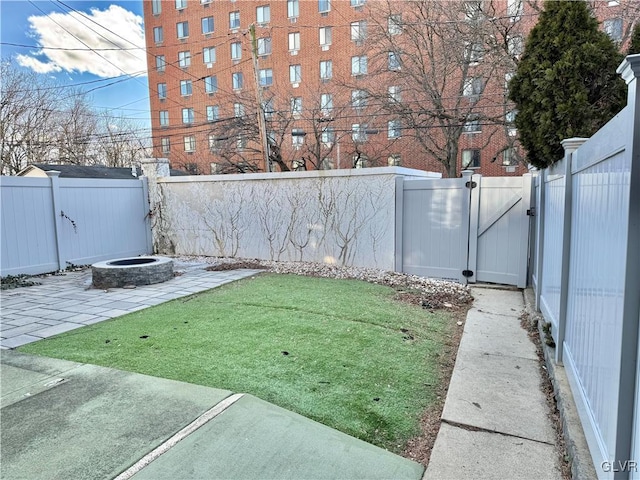 view of yard with a fenced backyard, a gate, a fire pit, and a patio