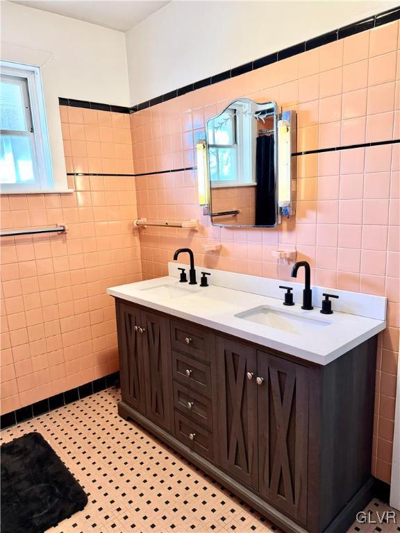 full bathroom featuring double vanity, a sink, and tile walls