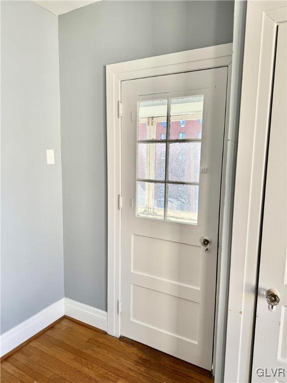 doorway with dark wood-style flooring and baseboards