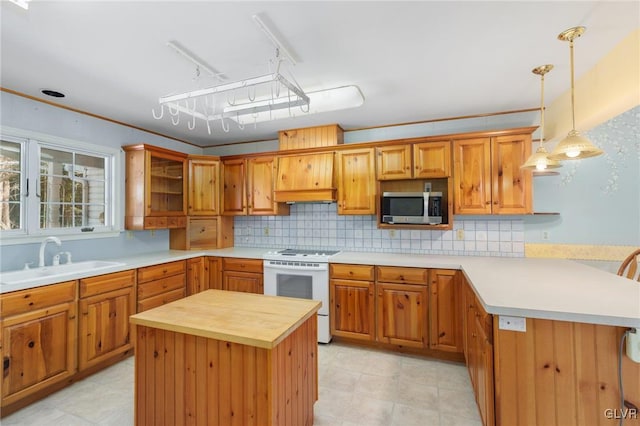 kitchen featuring white electric stove, a sink, a kitchen island, stainless steel microwave, and decorative light fixtures