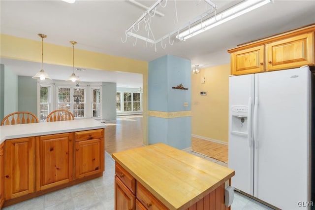 kitchen featuring a center island, pendant lighting, brown cabinetry, open floor plan, and white fridge with ice dispenser