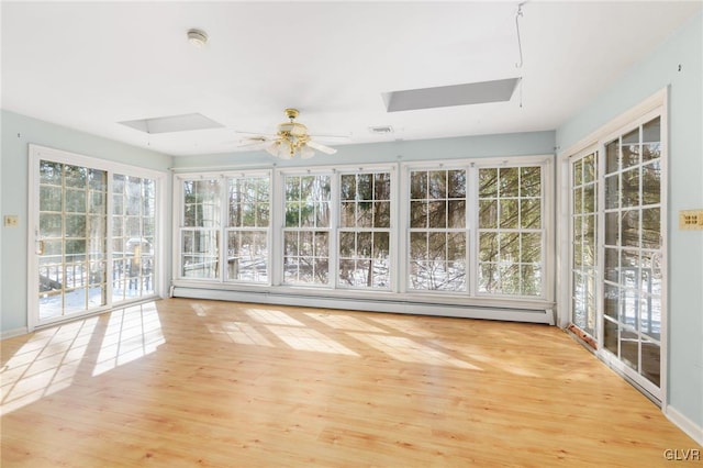 unfurnished sunroom with a ceiling fan, a skylight, visible vents, and a baseboard radiator