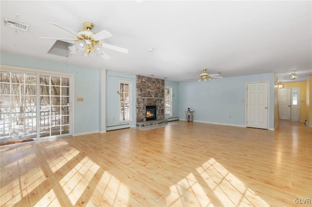 unfurnished living room with ceiling fan, a stone fireplace, a baseboard radiator, light wood-style flooring, and visible vents