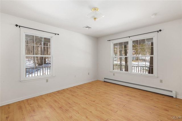 spare room with light wood-style flooring, visible vents, baseboard heating, and baseboards